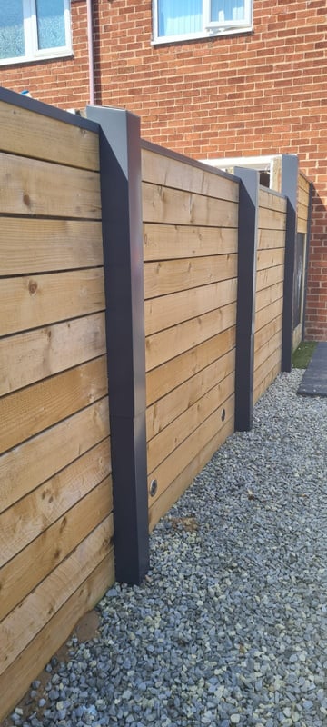 a wooden fence with black Seamline post covers and wooden slats